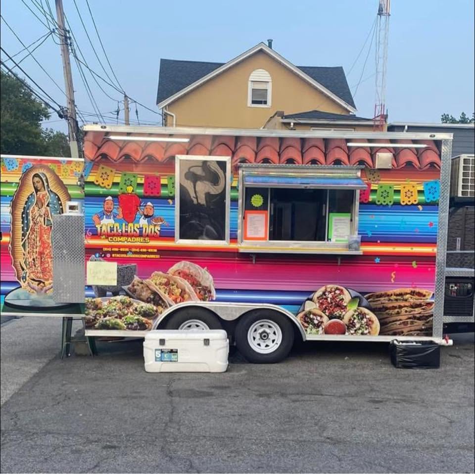 The Tacos Los Dos Compadres food truck, painted in bright serape colors, parked and ready to serve