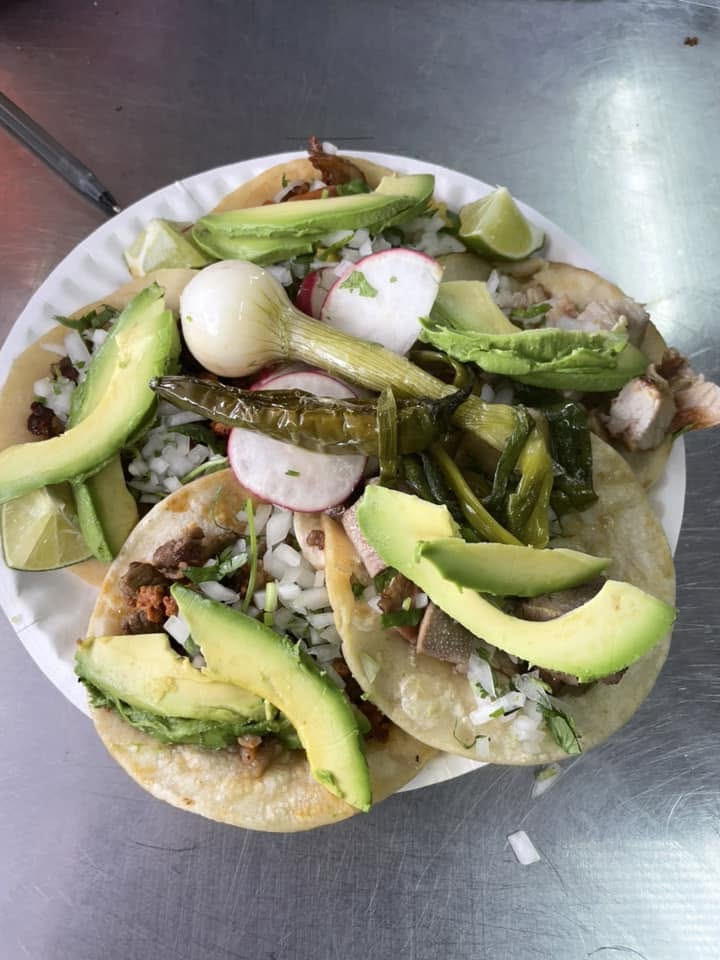 Tacos piled with sliced avocado, grilled spring onion, and radish